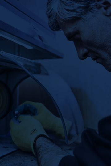 Ein Bildausschnitt im Hochformat eines Mannes, der ein Metallwarenteil an einer Maschine nacharbeitet. Das Bild ist mit einem blauen Layer bearbeitet.