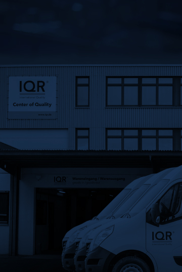 Ein Bildausschnitt vom IQR-Gebäude in Sindelfingen. Vor dem Gebäude stehen drei geparkte IQR-Transporter. Das Bild wird von einem dunkelblauen Layer überdeckt.